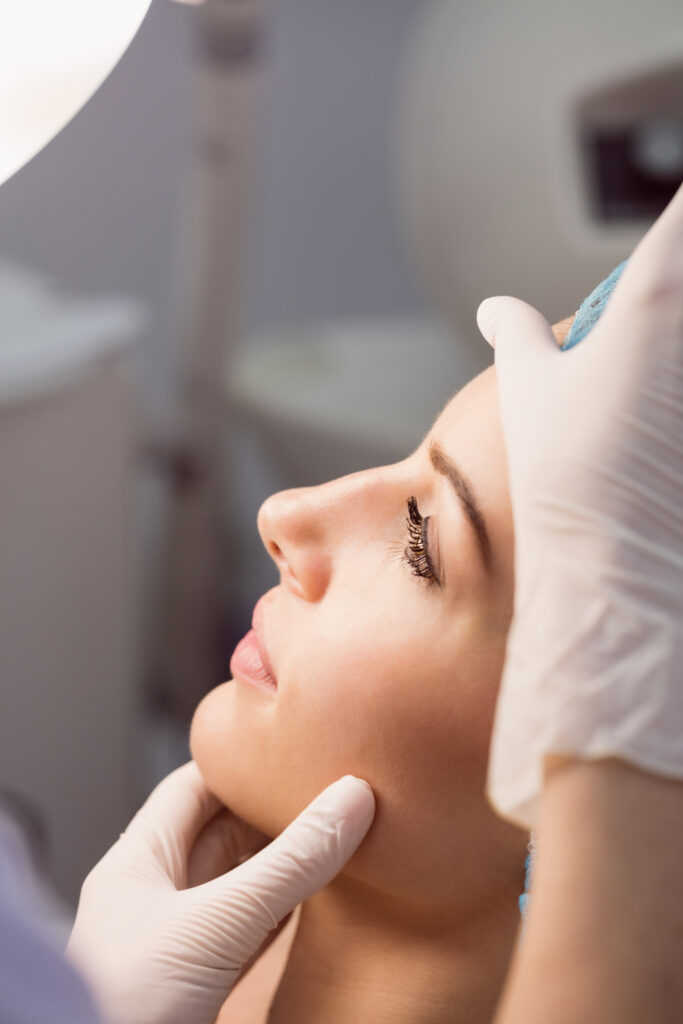 mano del doctor doctor examina cara de una mujer, para tratamiento cosmético